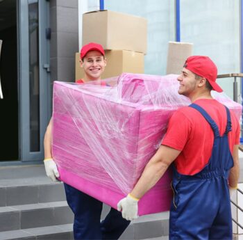 Umzug in Singen Zwei Umzugshelfer tragen ein in Folie gepacktes Möbelstück – Umzug in Singen
