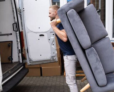 Möbellift Singen Möbellift Singen: Helfer tragen ein graues Sofa aus einem Transporter